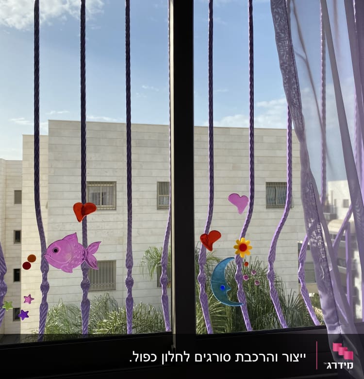 מדבקות צבעוניות על סורגי חלון עם וילון סגול